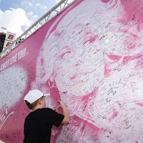 Henry Bailey, 7, from Kentucky signs his name to a tribute sign to the late Dolly Parton before a NASCAR Cup Series auto race Saturday, Sept. 19, 2026, in Bristol, Tenn. (AP Photo/Wade Payne)