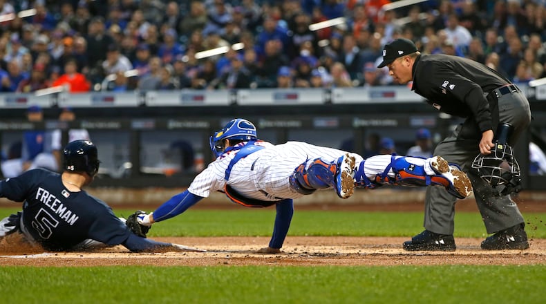 New York Mets catcher Travis d’Arnaud tries to tag the Braves’ Freddie Freeman during the first inning. Home plate umpire Cory Blaser is at right. Freeman was originally called out, but was ruled safe after a challenge by the Braves. (AP Photo/Kathy Willens)