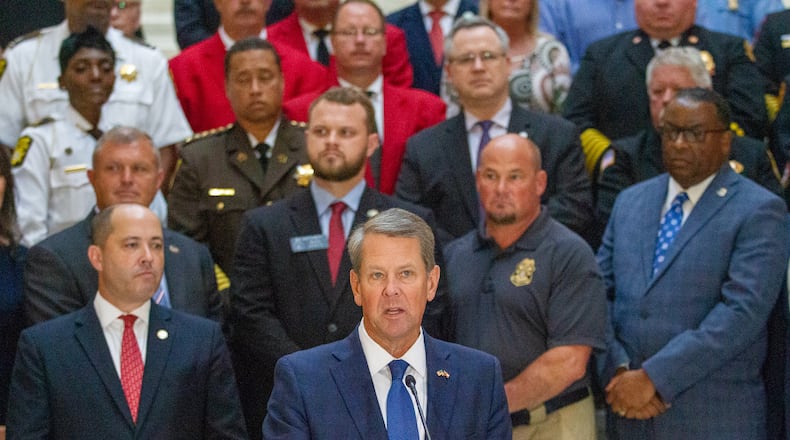 Gov. Brian Kemp, shown with law enforcement officials standing behind him at a press conference Monday at the Capitol, announced that first responders in the state will receive $1,000 bonuses. The money will come from a COVID-19 relief package that Democrats in Congress approved in March. STEVE SCHAEFER FOR THE ATLANTA JOURNAL-CONSTITUTION