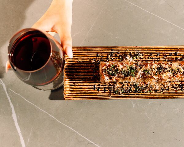 Overhead view of a sushi roll and a glass of red wine.