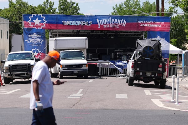 Volunteer passes by the stage for musical acts to perform at the Juneteenth celebration in the Five Points neighborhood where the event is staged Saturday, June 14, 2025, in Denver. (AP Photo/David Zalubowski)