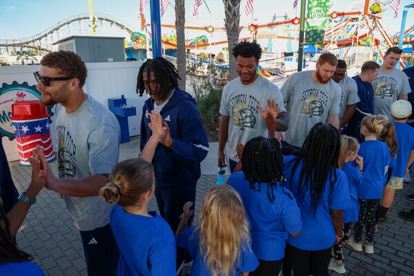 Tech football players Kyle Efford (from left), Elgin Sessions, AJ Hoffler, Keylan Rutledge, Ronald Triplette, Ronnie Thomas and Jameson Riggs greet children at an amusement park as part of Pop-Tarts Bowl festivities on Tuesday, Dec. 23, 2025 in Orlando, Fla. (Don Montague/Florida Citrus Sports)