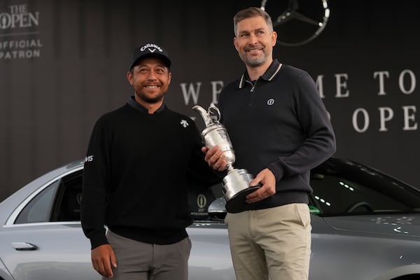 Xander Schauffele of the United States, left, winner of the 2024 British Open, hands back the Claret Jug trophy to the R&A CEO Mark Darbon ahead of the 2025 British Open golf championship at the Royal Portrush Golf Club, Northern Ireland, Monday, July 14, 2025. (AP Photo/Fransisco Seco)