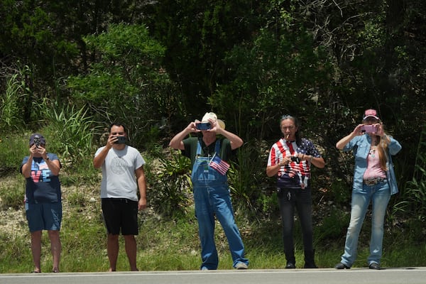 People watch as President Donald Trump and first lady Melania Trump pass in a motorcade in Kerrville, Texas, to monitor flood damage, Friday, July 11, 2025. (AP Photo/Jacquelyn Martin)