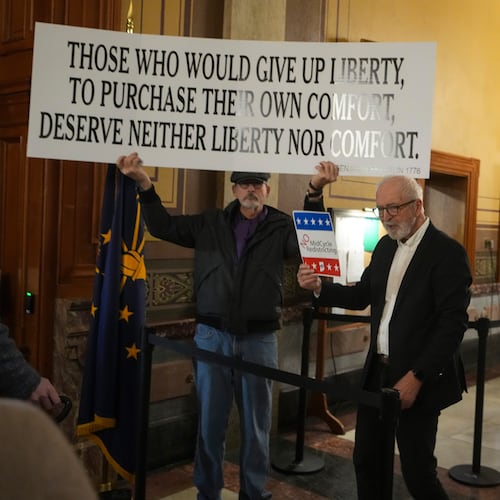 Protestors hold signs outside the Indiana Senate chamber before a vote to redistrict the state's congressional map at the Statehouse in Indianapolis, Thursday, Dec. 11, 2025. (AP Photo/Michael Conroy)
