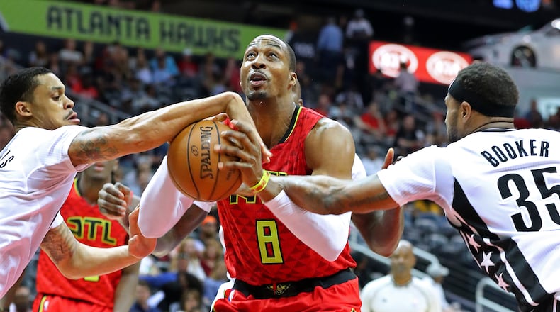 Hawks center Dwight Howard draws a foul on a rebound during a double team by Brooklyn Nets K.J. McDaniels (left) and Trevor Booker in a NBA basketball game on Sunday, March 26, 2017, in Atlanta.   Curtis Compton/ccompton@ajc.com