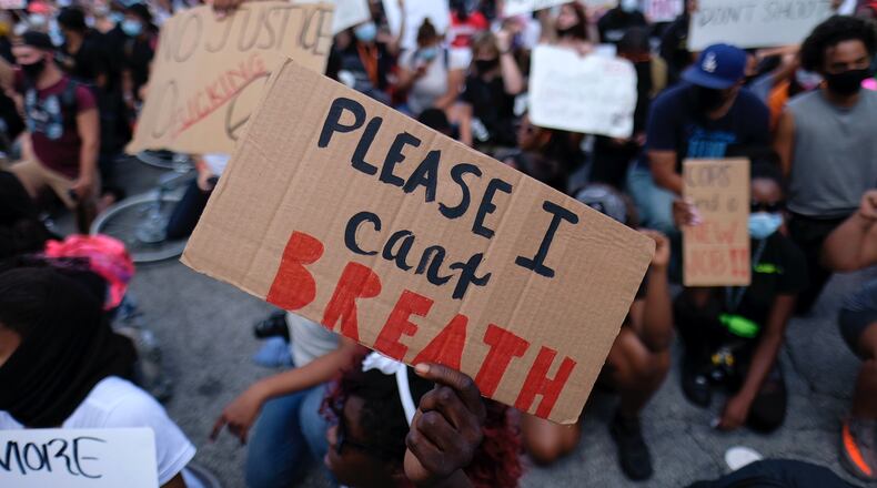 Protesters hold signs downtown on Monday. (Ben Gray for the Atlanta Journal Constitution)