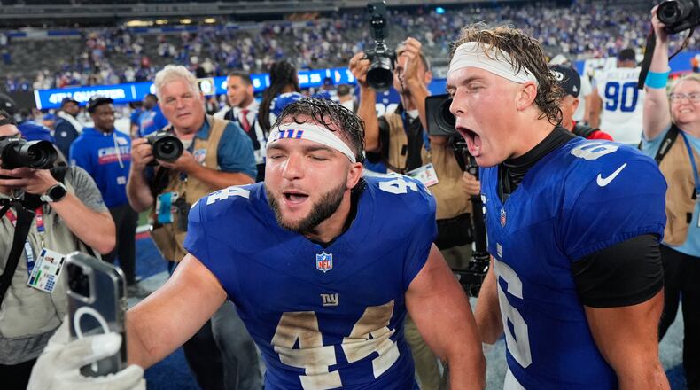 New York Giants running back Cam Skattebo (44) and quarterback Jaxson Dart (6) react with a cell phone following an NFL football game against the Dallas Cowboys Sunday, Sept. 13, 2026, in East Rutherford, N.J. (AP Photo/Yuki Iwamura)