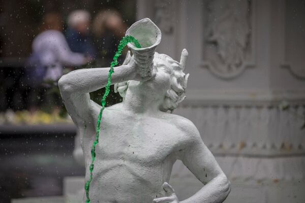A statue of a Greek mythical figure in the Forsyth Park fountain squirts green colored water from its cornucopia during the Greening of the Fountain event.
