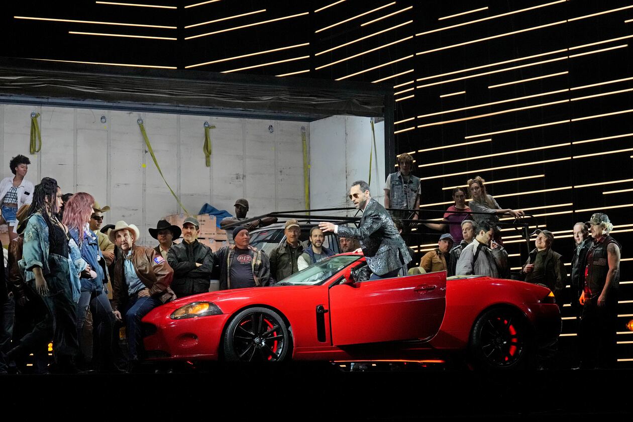 This image released by the Metropolitan Opera shows bass-baritone Kyle Ketelsen, in the red car, during a rehearsal of Bizet’s “Carmen” at the Metropolitan Opera in New York on Dec. 28, 2023. (Ken Howard/Met Opera via AP)