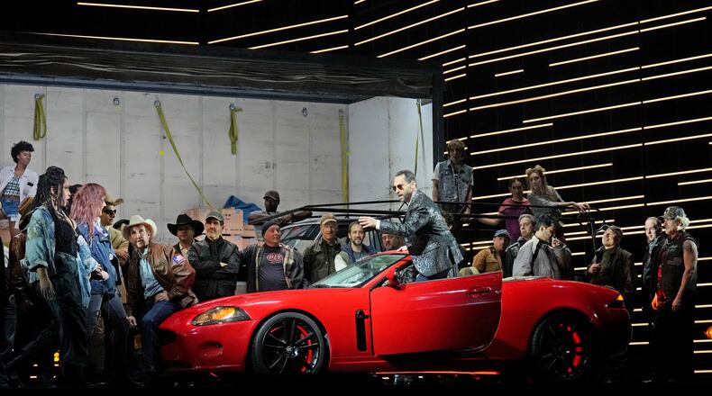 This image released by the Metropolitan Opera shows bass-baritone Kyle Ketelsen, in the red car, during a rehearsal of Bizet’s “Carmen” at the Metropolitan Opera in New York on Dec. 28, 2023. (Ken Howard/Met Opera via AP)