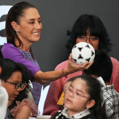 Mexican President Claudia Sheinbaum gives a soccer ball to children after her daily morning press conference at the National Palace in Mexico City, Thursday, April 30, 2026. (AP Photo/Fernando Llano)