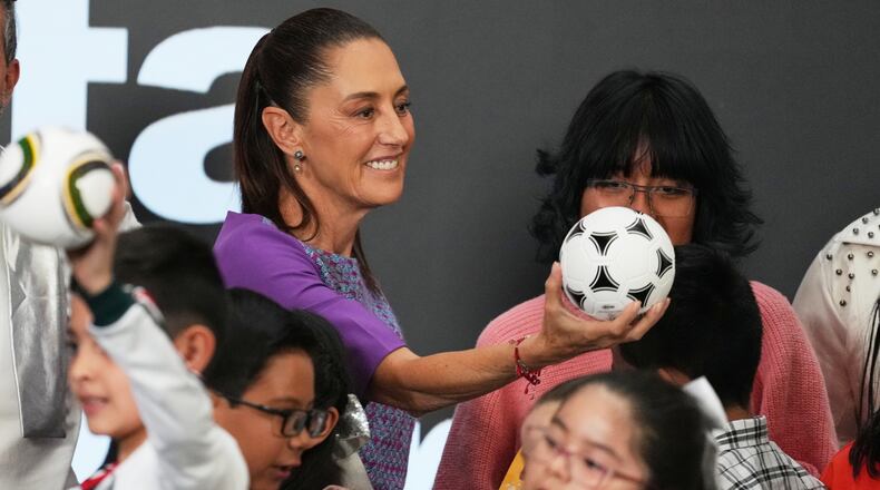 Mexican President Claudia Sheinbaum gives a soccer ball to children after her daily morning press conference at the National Palace in Mexico City, Thursday, April 30, 2026. (AP Photo/Fernando Llano)