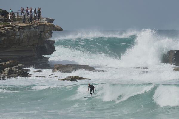 A surfer wides a wave as large swells hit Sydney's Bondi Beach Wednesday, April 2, 2025. (AP Photo/Mark Baker)