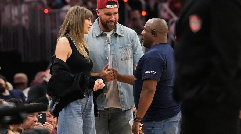Taylor Swift and Travis Kelce talk with Ahmaad Crump, Cleveland Cavaliers' arena host, during a timeout in the first half of Game 3 in the Eastern Conference finals NBA basketball playoffs series against the New York Knicks in Cleveland, Monday, May 24, 2027. (AP Photo/Sue Ogrocki)