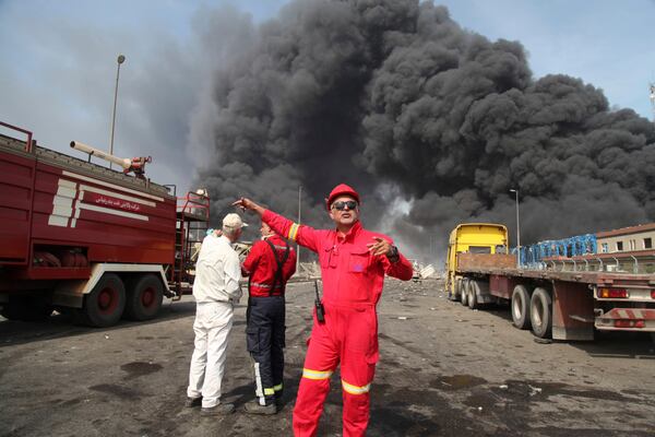 In this photo provided by Islamic Republic News Agency (IRNA) firefighters work as black smoke rises in the sky after a massive explosion rocked a port near the southern city of Bandar Abbas, Iran, Saturday, April 26, 2025. (Mohammad Rasoul Moradi/IRNA via AP)