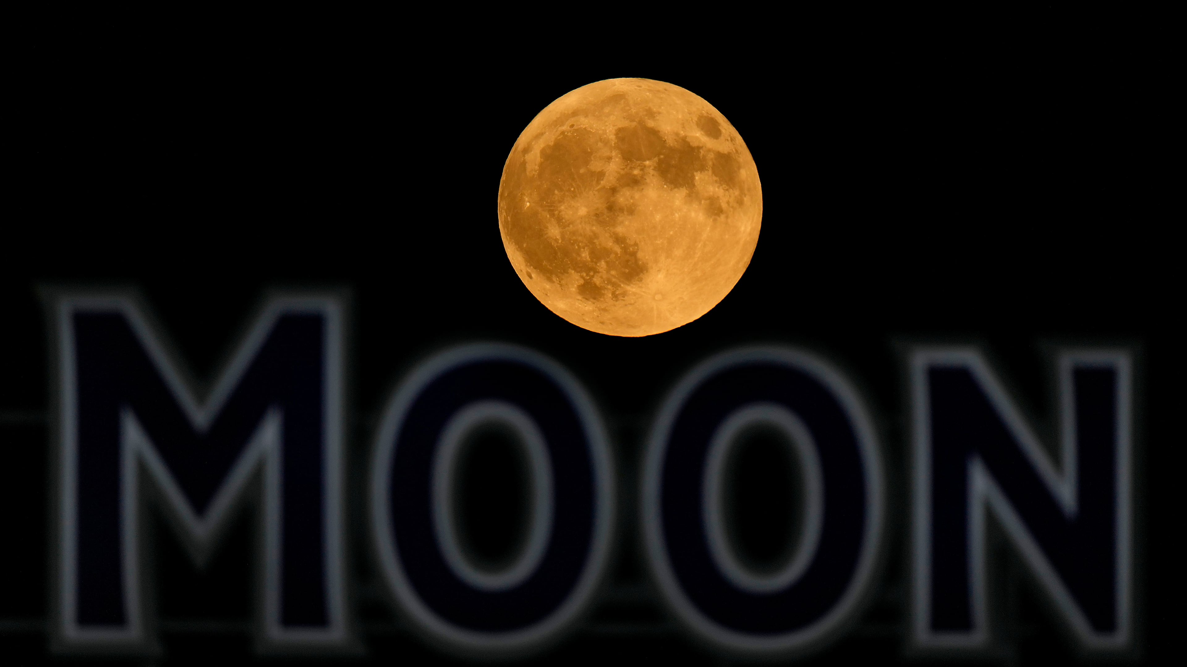 FILE - The full moon rises in the over a beer sign in the outfield at Kauffman Stadium during a baseball game between the Kansas City Royals and the Detroit Tigers, Tuesday, Sept. 17, 2024, in Kansas City, Mo. (AP Photo/Charlie Riedel, File)