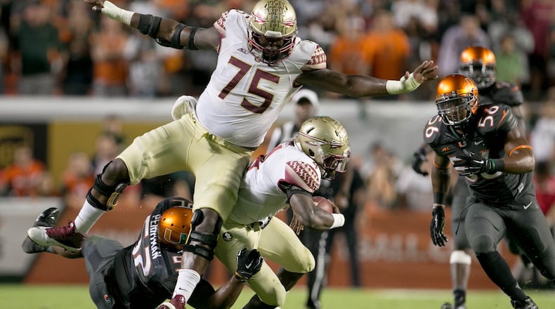 Florida State Seminoles running back Dalvin Cook (4) runs into his blocker offensive tackle Cameron Erving (75) as he is tackled by Miami Hurricanes linebacker Denzel Perryman (52) at Sun Life Stadium in Miami Gardens, Florida on November 15, 2014. (Allen Eyestone / The Palm Beach Post)