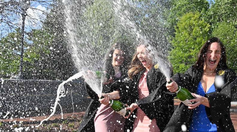 Emory graduate candidates for the class of 2020 (from left) Katie Matuska, Liz Olinde and Izzy Saridakis spray Champagne as they celebrate at Emory's Haygood-Hopkins Gate in Decatur on Saturday, April 25, 2020. They were all roommates and wanted to celebrate their graduation together since they may only have a virtual graduation ceremony this year. (Hyosub Shin / Hyosub.Shin@ajc.com)