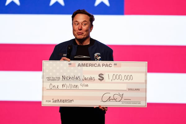 Elon Musk speaks at a town hall holding a check Sunday, March 30, 2025, in Green Bay, Wis. (AP Photo/Jeffrey Phelps)