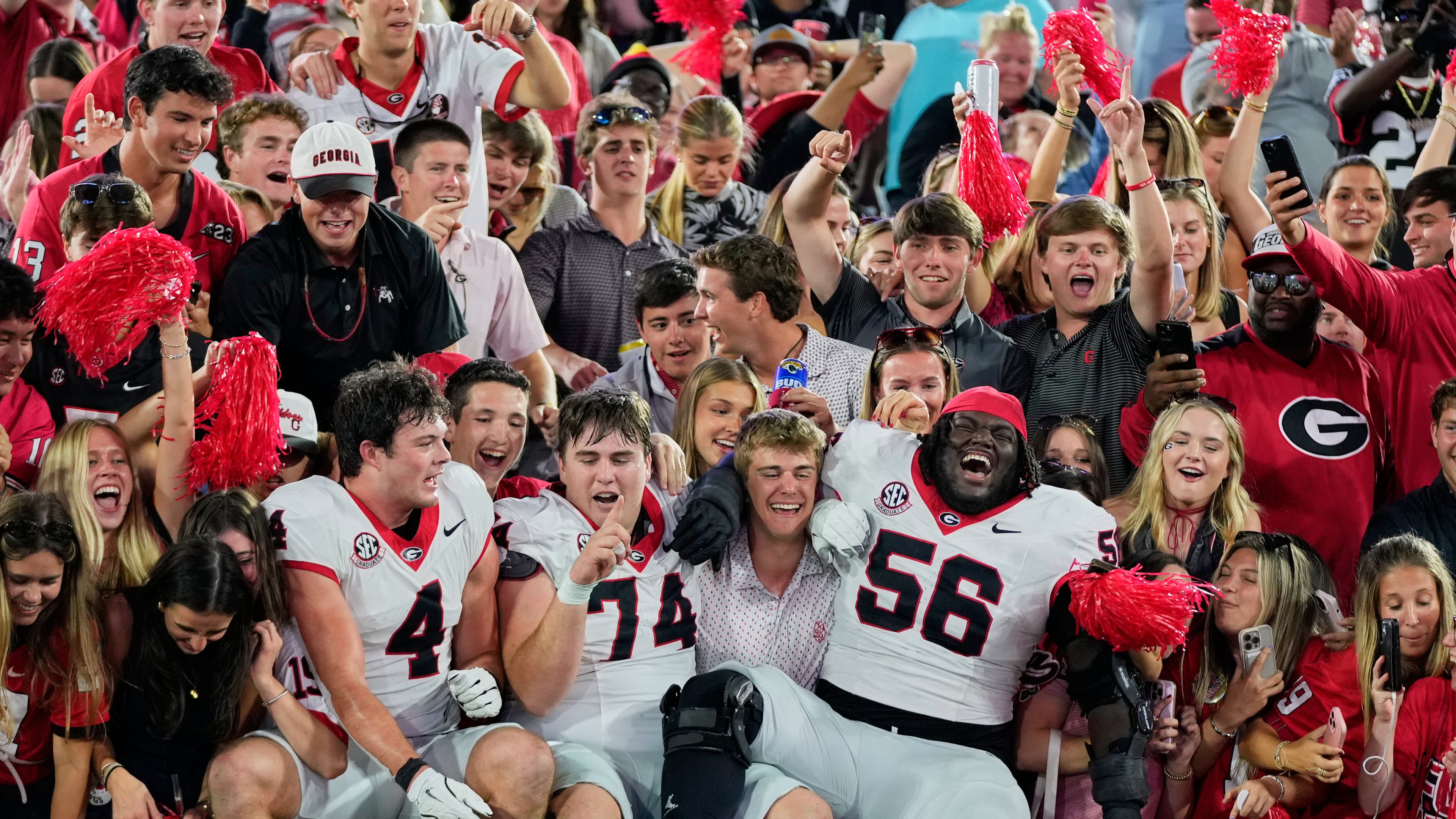 Georgia players tight end Oscar Delp (4), offensive lineman Drew Bobo (74) and offensive lineman Micah Morris (56) celebrate with fans after defeating Florida in an NCAA college football game Saturday, Nov. 1, 2025, in Jacksonville, Fla. (AP Photo/John Raoux)