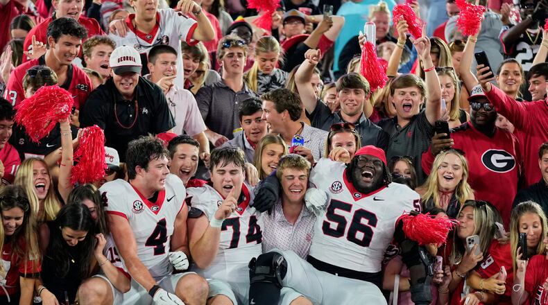 Georgia players tight end Oscar Delp (4), offensive lineman Drew Bobo (74) and offensive lineman Micah Morris (56) celebrate with fans after defeating Florida in an NCAA college football game Saturday, Nov. 1, 2025, in Jacksonville, Fla. (AP Photo/John Raoux)