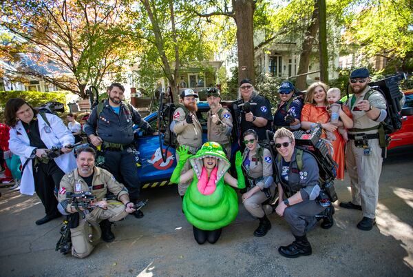The Atlanta Ghostbusters gather in front of an Ectomobile replica on Euclid Avenue before the annual Little 5 Points Halloween Parade on Sunday, Oct 20, 2024. The group includes (from left) TJ Scheitler, Dustin Grau, Joseph Ricciardelli, Jonathan Mitchell, Jonathon McCoy, Brad Peters, Kevin Looney, Chelsea Ritter-Jones holding 8-month old Logan Jones, Marcus Jones, Cara Davis as Slimer (center front), Carolyn Hinkle and Neil Hinkle. (Jenni Girtman for the AJC)