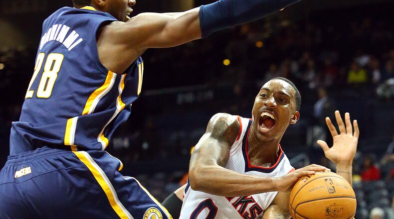 Hawks point guard Jeff Teague is forced to pass it off under the basket by Indiana Pacers center Ian Mahinmi during the second half of their NBA preseason basketball game on Tuesday, Oct. 22, 2013, in Atlanta.