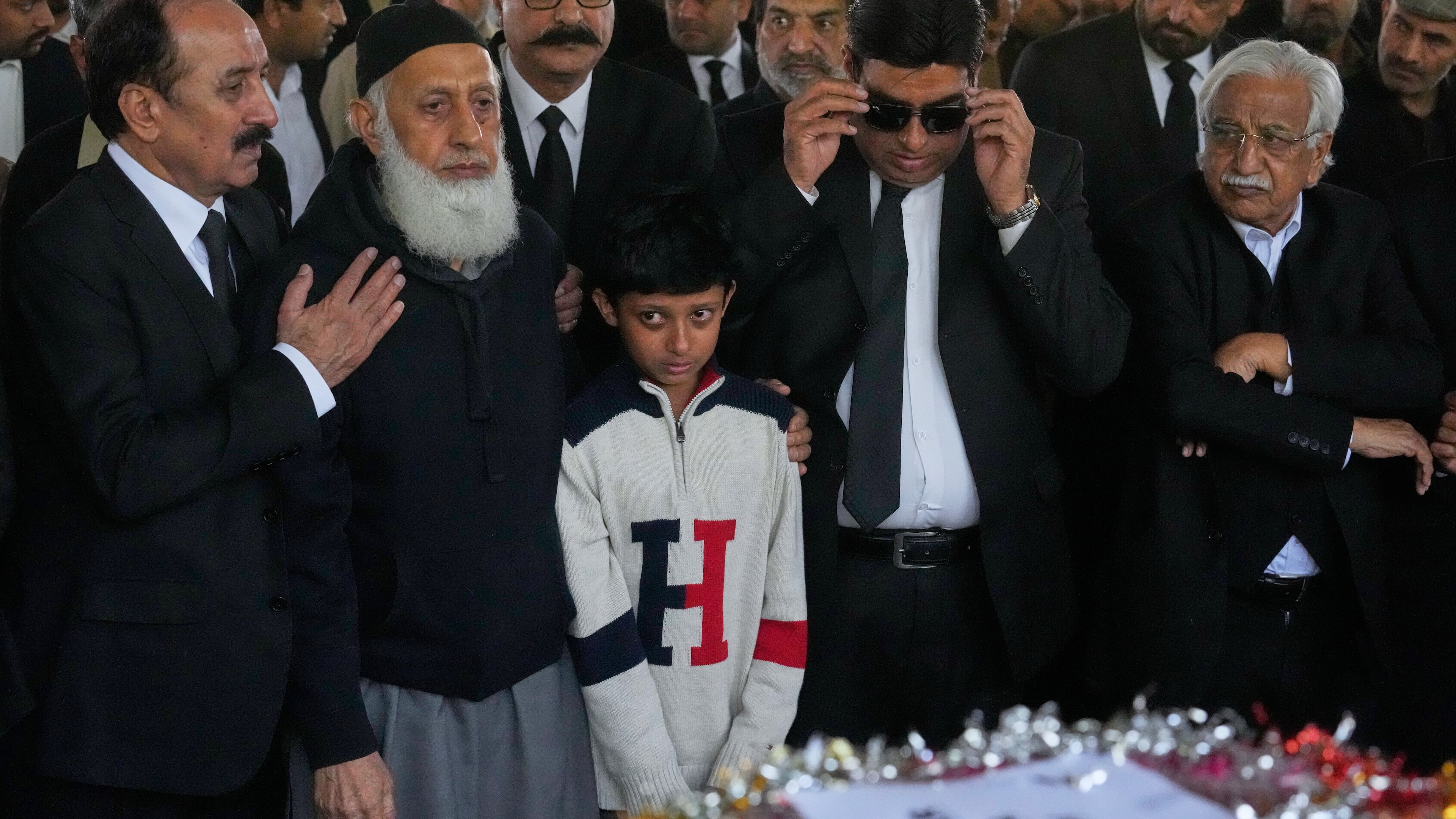 Mourners comfort Yahya Zubair, son of lawyer Zubair Aslam Ghumman, who was killed in Tuesday's suicide bombing outside the gates of a district court, during a funeral prayer, in Islamabad, Pakistan, Wednesday, Nov. 12, 2025. (AP Photo/Anjum Naveed)