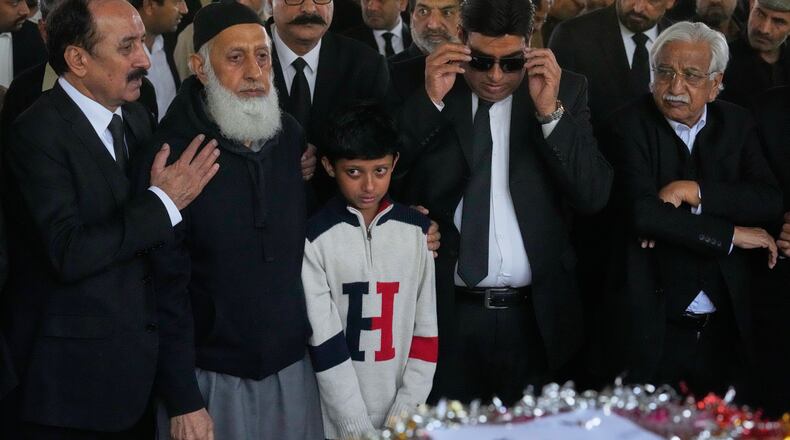 Mourners comfort Yahya Zubair, son of lawyer Zubair Aslam Ghumman, who was killed in Tuesday's suicide bombing outside the gates of a district court, during a funeral prayer, in Islamabad, Pakistan, Wednesday, Nov. 12, 2025. (AP Photo/Anjum Naveed)