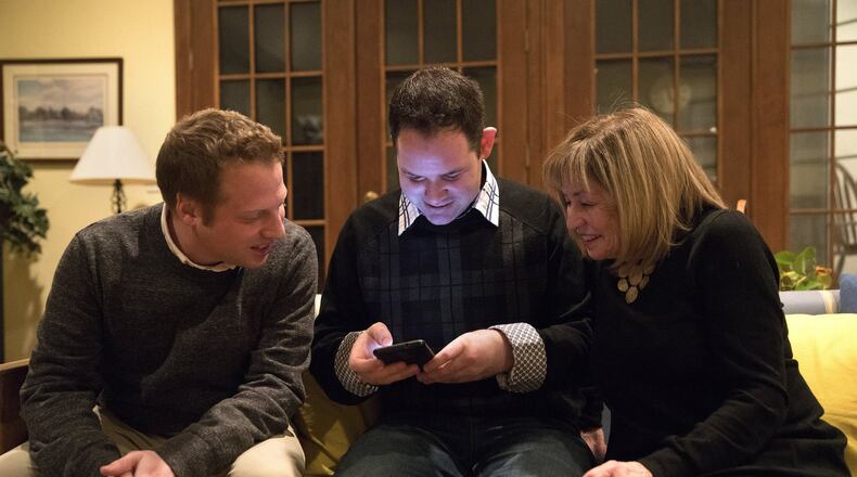 Steve Anderson, center, looks at his Glimmer dating profile on his smart phone with his mother Christine and brother Geoff on Saturday, Feb. 4, 2017 at their home in Kenilworth, IL. Anderson, who has cognitive disabilities, inspired his brother Geoff to create the lifestyle application, which aims to make online dating and socializing easier for adults with disabilities. (Erin Hooley/Chicago Tribune/TNS)