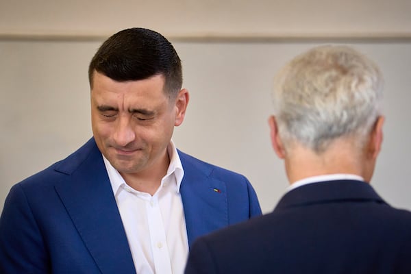 Presidential candidate George Simion grimaces next to Calin Georgescu, winner of the first round of last year's annulled election, before casting his vote in the second round of the country's presidential election redo in Mogosoaia, Romania, Sunday, May 18, 2025. (AP Photo/Vadim Ghirda)