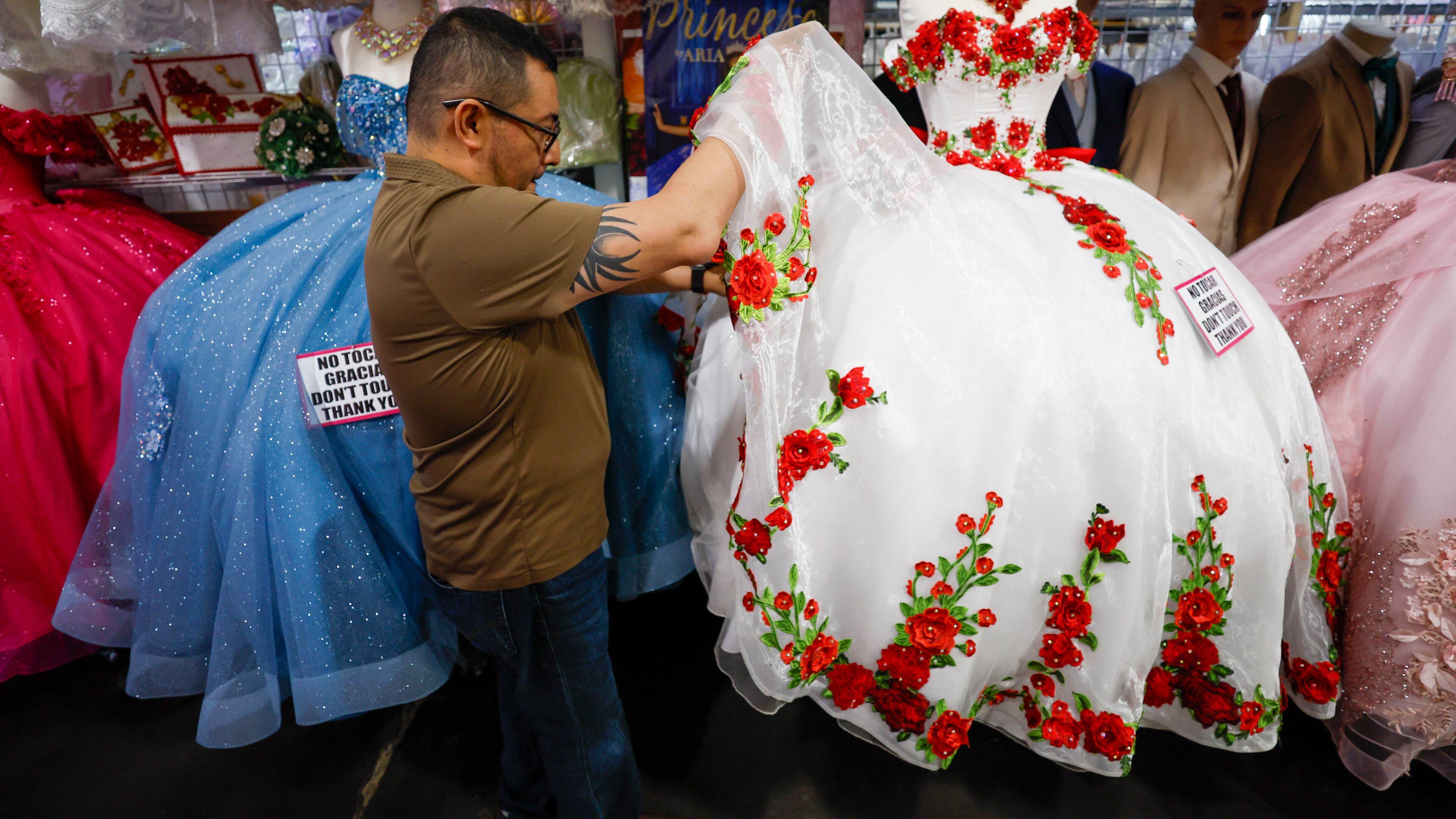 Frank Chavez, owner of Lizzy Fashion, arranges a quinceañera dress at his shop in Plaza Fiesta, May 7, 2025. (Miguel Martinez/AJC)