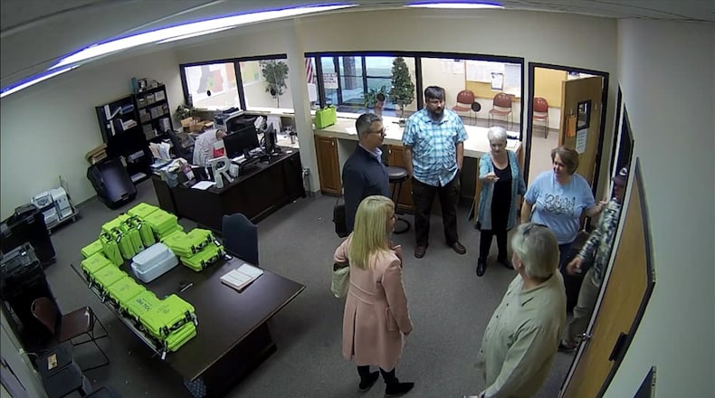 Surveillance video of the Coffee County election office shows green voter check-in tablets, called PollPads, on a table while tech experts and supporters of then-President Donald Trump examine election equipment on Jan. 7, 2021, the day after a mob attacked the U.S. Capitol. 
From left: computer analysts Paul Maggio, Jennifer Jackson and Jim Nelson of the data firm SullivanStrickler; Cathy Latham, a member of the Georgia Republican Party's executive committee; Ed Voyles, a former Coffee County elections board member; Misty Hampton, the county's elections director; and Eric Chaney, a Coffee County elections board member. Source: Coffee County