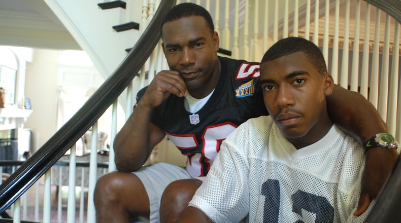 Former Falcons linebacker Jessie Tuggle (left) with his son Justin Tuggle, when Justin was a senior and quarterback at Northview High School. Justin Tuggle now plays with the Houston Texans. (RENEE BROCK/AJC file)