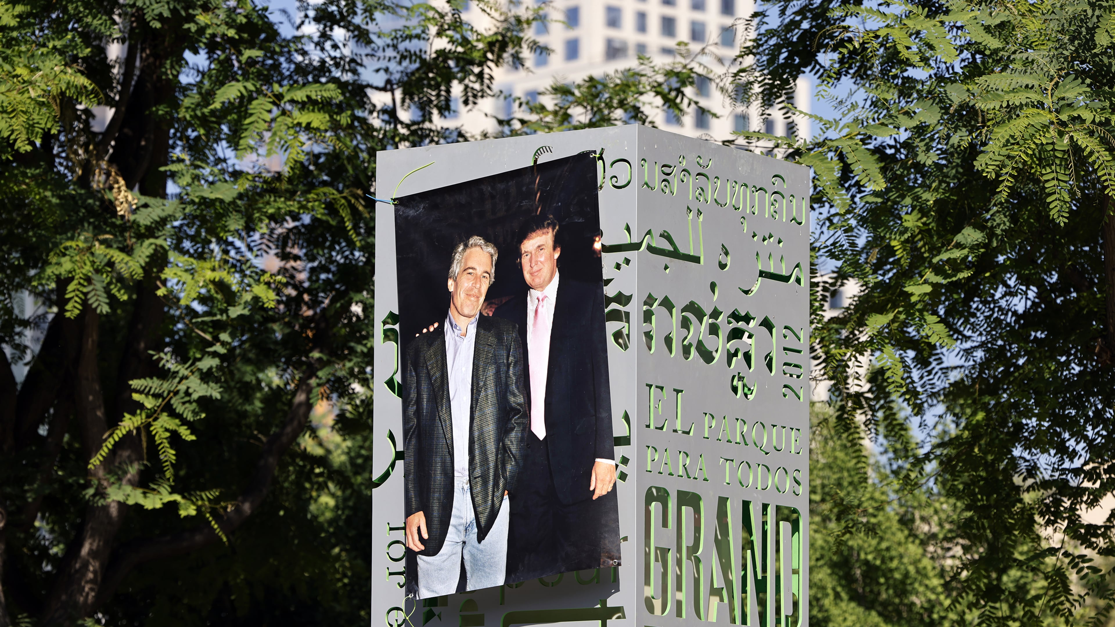 A 1997 photograph of the late Jeffrey Epstein (left) and Donald Trump was posted on a sign at Gloria Molina Grand Park in Los Angeles in June. (TNS)