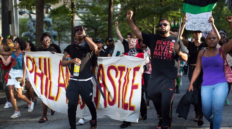 Demonstrators carry signs as they march down Peachtree Street to Piedmont Park, Thursday, July 7, 2016, in Atlanta. Demonstrators gathered in response to the death of 37-year-old Alton Sterling, who was killed by Baton Rouge police outside of a convenience store where he was selling CDs and Philando Castile, who was shot and killed when Minnesota police stopped him for a traffic violation on Wednesday evening. BRANDEN CAMP/SPECIAL