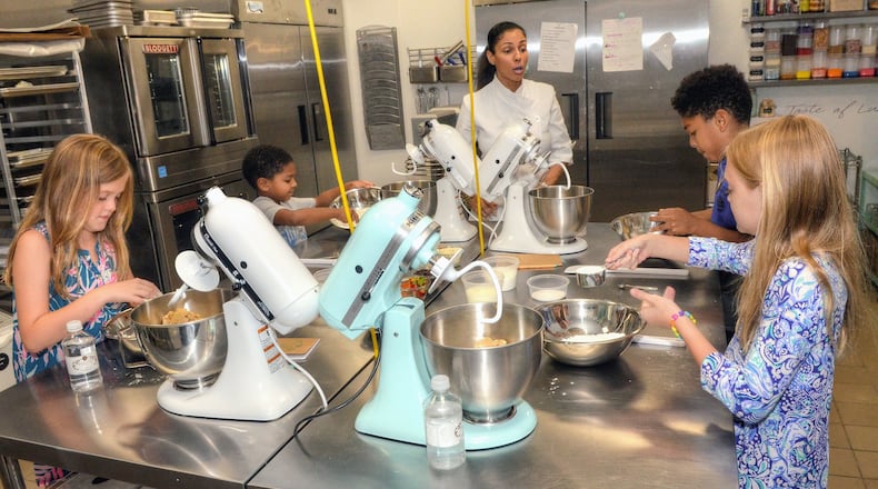 A Haute Cookie owner Shiana White (center) instructs students (starting from left front and going clockwise) Harper Wright, 9, Jacadi Robinson, 8, Gionne Robinson, 10, and Alden Wright 9, during their lesson in making Edible Sugar Cookie Dough in the kitchen of A Haute Cookie. Gionne and Jacadi are White’s sons. CONTRIBUTED BY CHRIS HUNT PHOTOGRAPHY