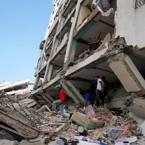 Residents walks through the rubble two days after earthquakes struck Catia La Mar, Venezuela, Friday, June 26, 2026. (AP Photo/Fernando Vergara)