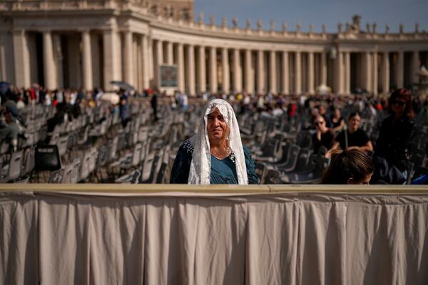 A woman sits in St. Peter's Square as people wait to pay their respects to the late Pope Francis, who will lie in state at St. Peter's Basilica for three days, at the Vatican, Wednesday, April 23, 2025. (AP Photo/Andreea Alexandru)