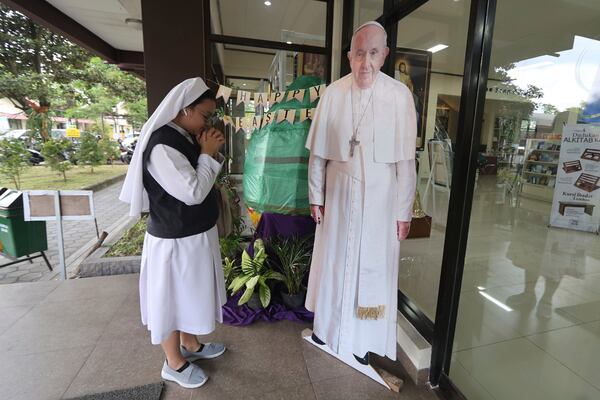 A Catholic nun prays in front of a cutout of Pope Francis in Yogyakarta, Indonesia, Monday, April 21, 2025. (AP Photo/Slamet Riyadi)
