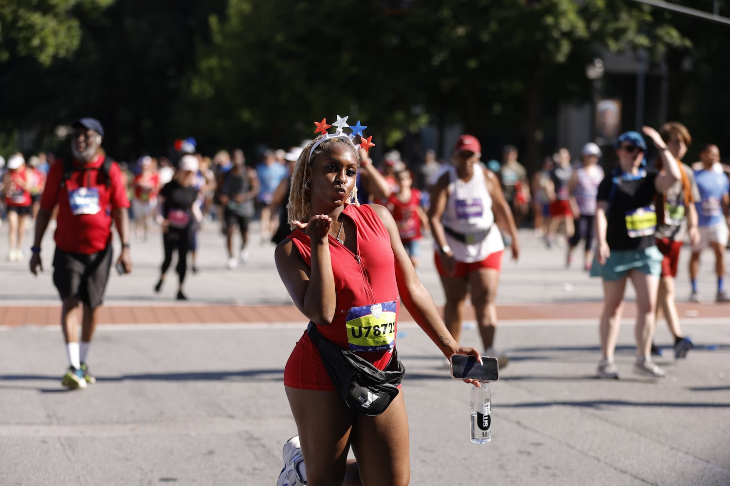 A runner blows a kiss while on the course at  the 56th running of the Atlanta Journal-Constitution Peachtree Road Race in Atlanta on Friday, July 4, 2025.   (Natrice Miller / AJC)