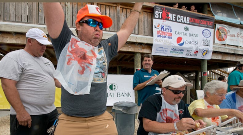 In this photo provided by the Florida Keys News Bureau, Aaron Sutcliffe raises his hands in victory after cracking and cleanly consuming 25 medium stone crab claws in 14 minutes and 20 seconds Saturday, Oct. 17, 2015, at Keys Fisheries Restaurant in Marathon, Fla. He won the Stone Crab Eating Contest in the Florida Keys, which awarded individual and team honors to participants who turned in the fastest times for cracking and cleanly consuming 25 stone crab claws. (Andy Newman/AP Photo via the Florida Keys News Bureau)