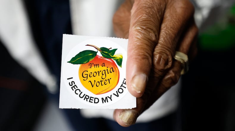 A poll worker holds a Georgia voter sticker ready to be handed to a voter at Berean Christian Church on Oct. 17, 2022. (Miguel Martinez/The Atlanta Journal-Constitution/TNS)