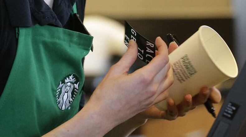 In a Wednesday, March 18, 2015, file photo, Holly Ainslie, a barista at a Starbucks store in Seattle, puts a "Race Together" sticker on a customer's cup. Starbucks baristas will no longer write "Race Together" on customers' cups starting March 22, 2015, ending as planned a visible component of the company's diversity and racial inequality campaign, according to a memo.