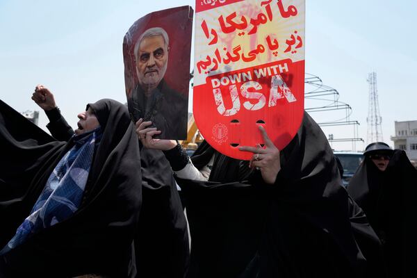 An Iranian protester holds up an anti-U.S. placard and a poster of the late revolutionary guard Gen. Qassem Soleimani, who was killed in a U.S. attack in Iraq in 2020, in an anti-Israeli gathering in Tehran, Iran, Friday, June 13, 2025. (AP Photo/Vahid Salemi)