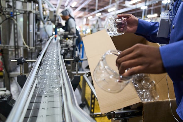 A factory worker at McBride Research Laboratories in Decatur, Ga., places plastic jars on a conveyor belt to be filled with a treatment hair mask for the company's Design Essentials product line, Monday, May 5, 2025. (AP Photo/Stephanie Scarbrough)