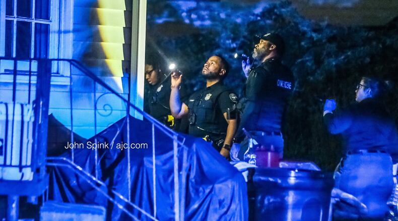 Atlanta police officers look for bullet holes in the side of a home in the 1100 block of Kipling Street where a 61-year-old woman was shot Wednesday morning.