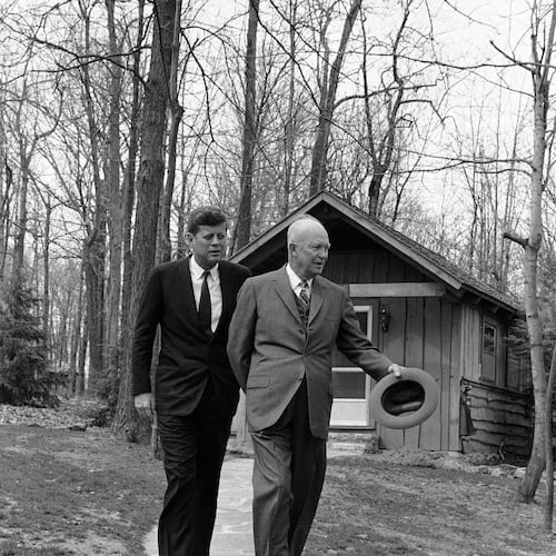 FILE - President John Kennedy and former President Dwight Eisenhower walks along a flagstone path, in perfect step at Camp David, atop of mountain near Thurmont, Maryland on April 22, 1961 after they flew there to discuss the Cuban crisis. In background is one of the lodges at the camp. (AP Photo, File)
