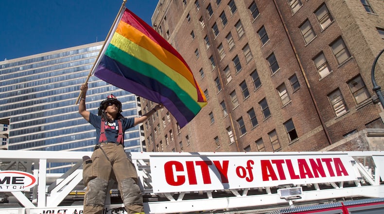 An Atlanta firefighter waves a Rainbow Flag while standing on a fire truck at the start of the Atlanta Pride Parade in 2016.